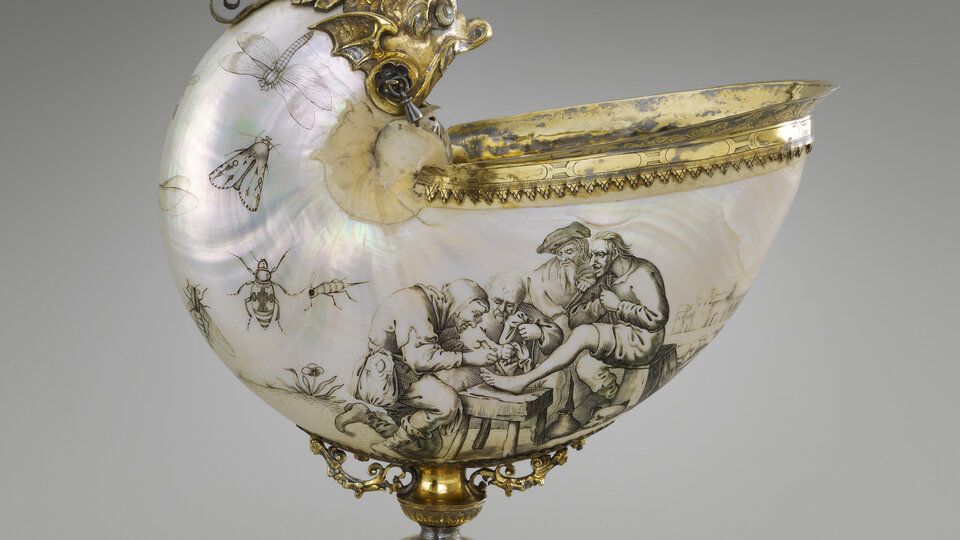 A stemmed cup. The cup itself resembles a shell. It has an iridescent surface that is decorated with images of insects as well as a scene involving four figures. The opening faces directly up and is fitted with a flared, gold-colored lip. A curved section of the shell rises vertically above and alongside the opening and terminates in a gold-colored face, perhaps that of a bird. The shell is supported underneath by an ornate stem on a broad, two-tiered base.