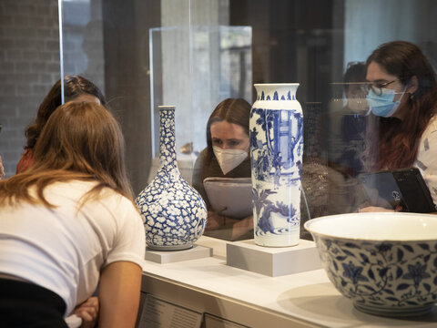Students examining ceramics in display cases.