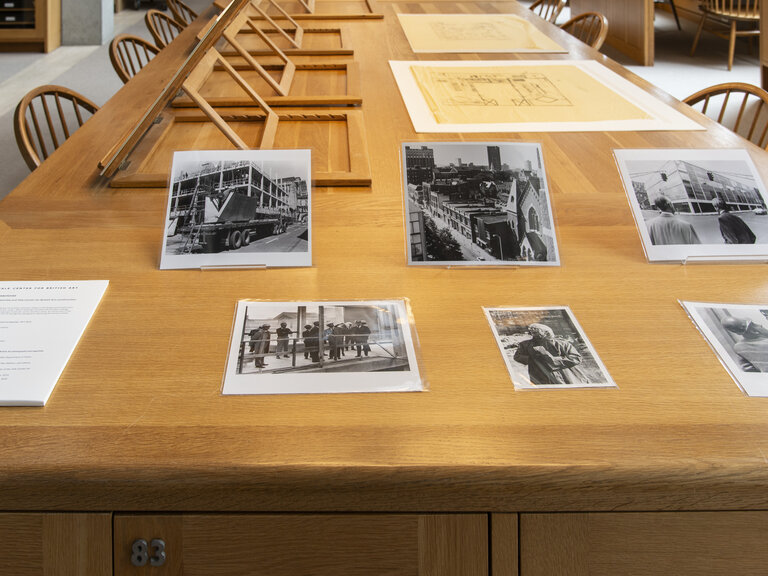 Photographs, papers, and other materials arrayed on a long wooden desk.
