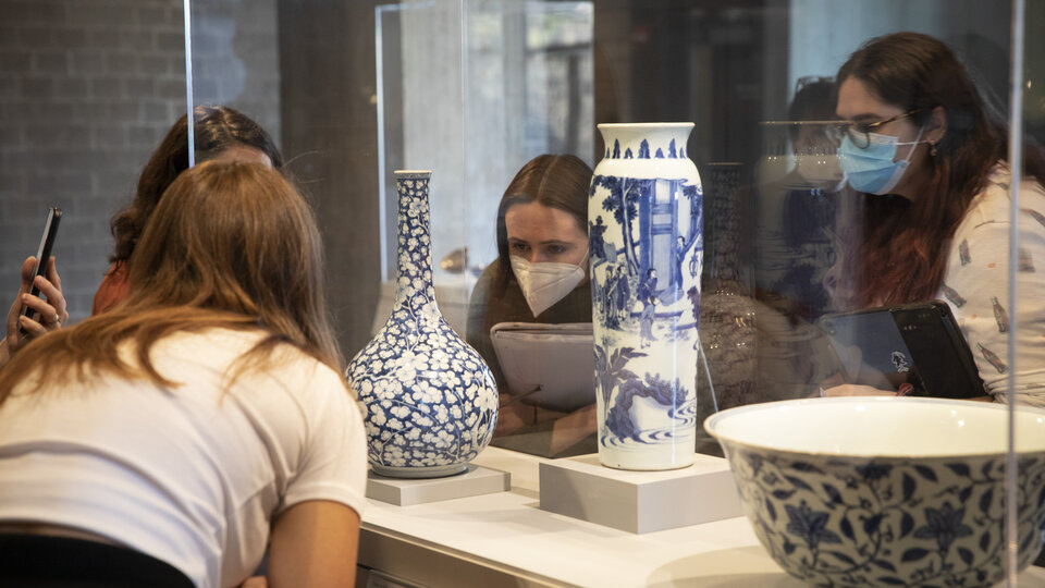 Students examining ceramics in display cases.