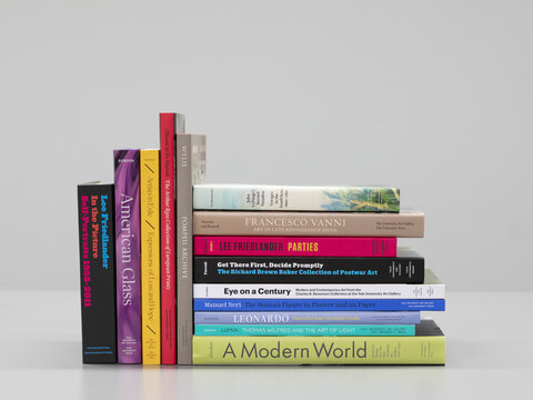 A collection of books with colorful spines. Some of the books are standing and the others are stacked