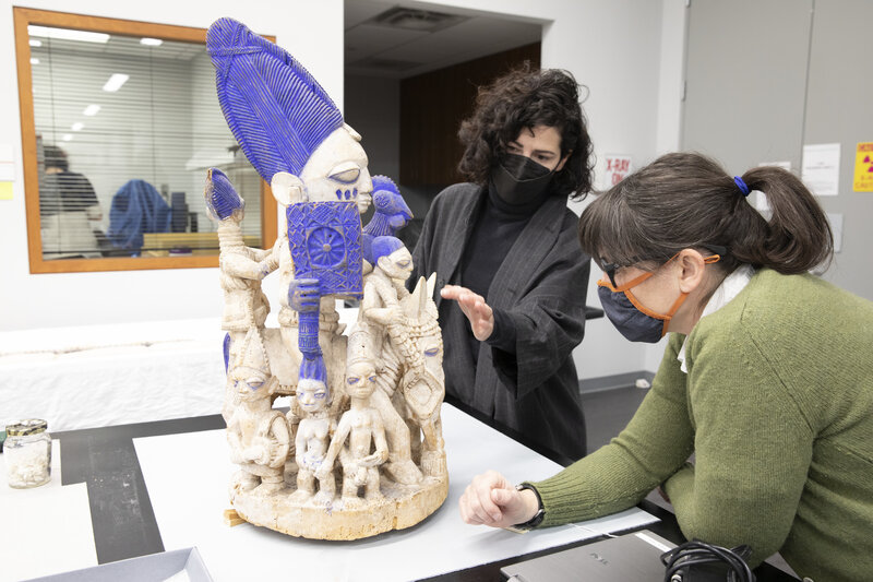 Two conservators looking at an African sculpture on the lab.
