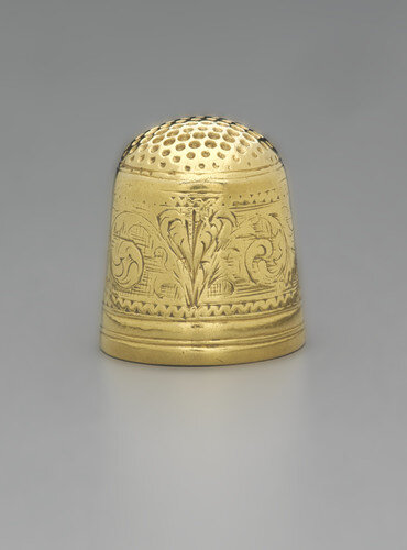 Gold thimble punched with small indentations at the top for pushing a needle and its sides engraved with foliate scrolls.