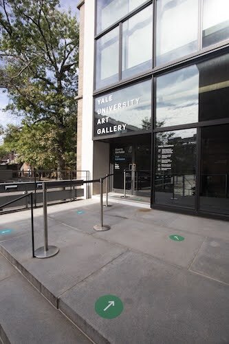 Entrance to Gallery with green directional stickers on the walkway each six feet apart.