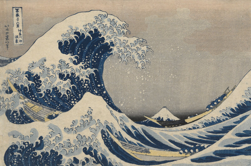 A large, breaking wave occupies almost the entire left half of this woodblock print image. Two long, shallow boats navigate the surrounding choppy waters, and a snow-capped mountain visible in the distance.